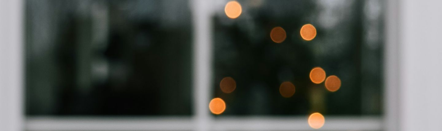 Fenêtre éclairée par un sapin de Noël et des guirlandes lumineuses