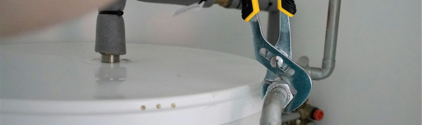 Technicien serrant un raccord de chauffe-eau avec une pince