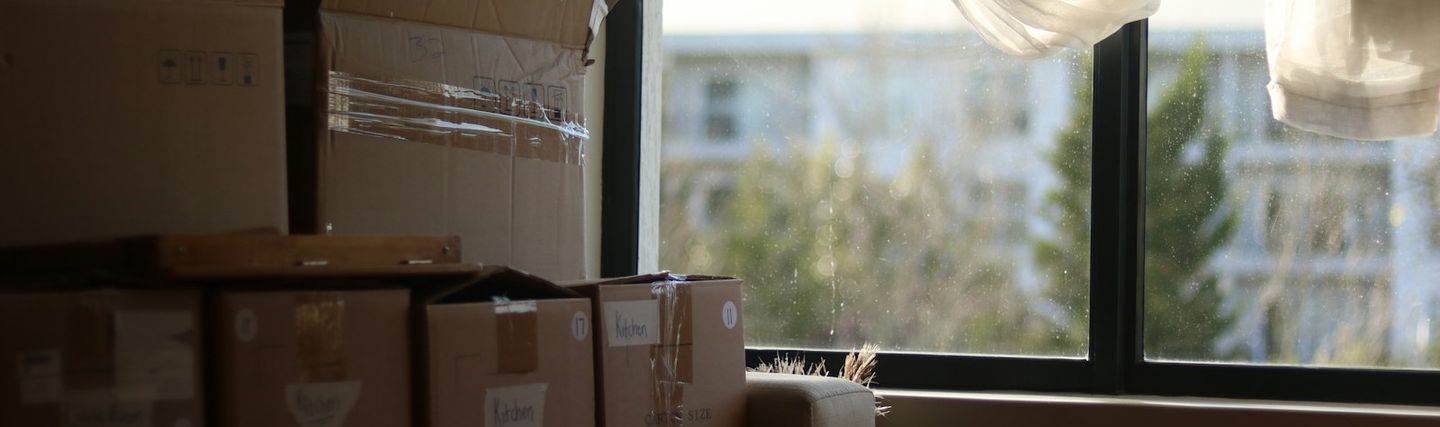 Cartons de déménagement empilés dans une pièce claire devant une fenêtre